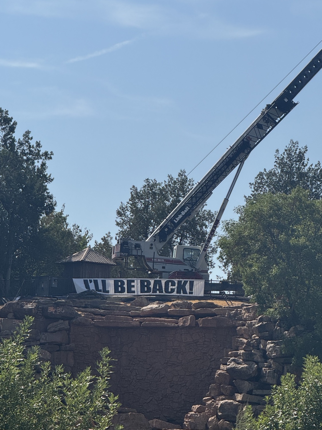 Kingdom Cranes Link-Belt truck crane lifting at a rock structure job site with an 'I'll be back!' banner